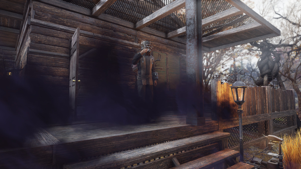 Fallout 76 - seorang pemain berbaju penuh kultus Mothman berdiri di beranda, yang terselubung asap hitam pekat.