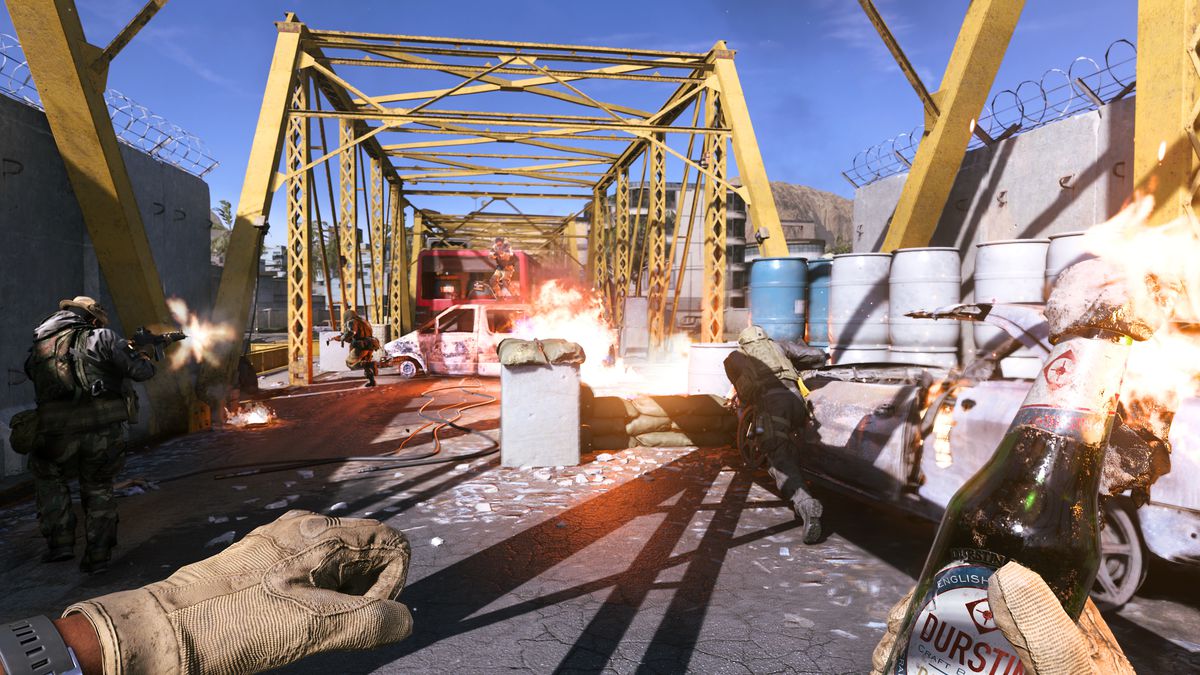 dalam tangkapan layar orang pertama dari Call of Duty: Modern Warfare (2019), seorang pemain di jembatan rangka kuning memegang bom molotov yang terbuat dari botol bir