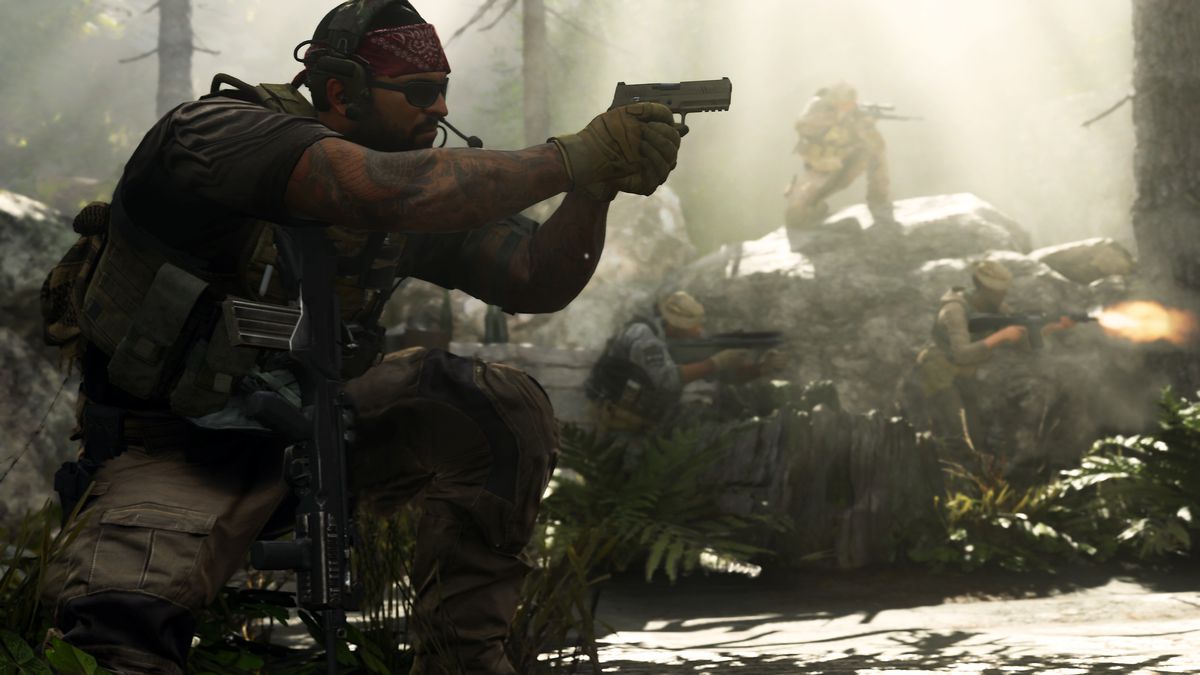Seorang pemain yang mengenakan kacamata hitam dan bandana membidikkan pistol di hutan berbatu, dengan beberapa rekan tim di latar belakang, dalam tangkapan layar dari Call of Duty: Modern Warfare (2019)