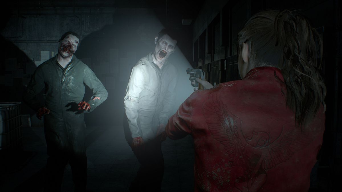 Claire Redfield mengarahkan revolver dan senternya ke sepasang zombie dalam tangkapan layar dari pembuatan ulang Resident Evil 2.