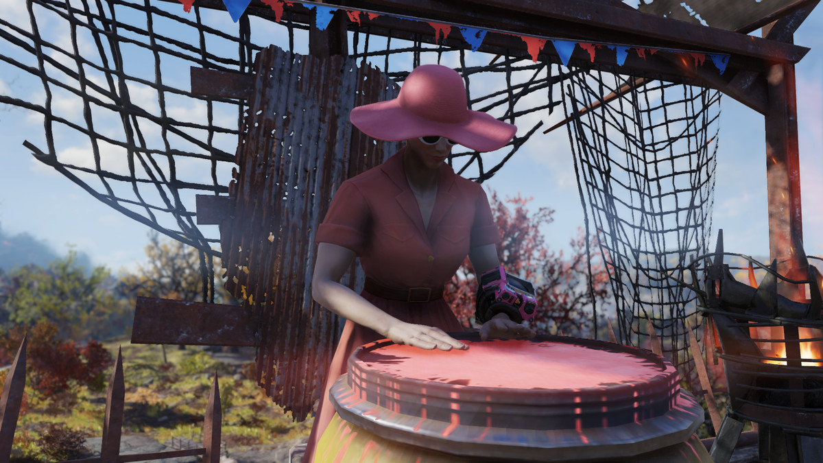 Fallout 76 - seorang wanita dalam gaun merah muda dan sunhat memainkan drum pada per barel.