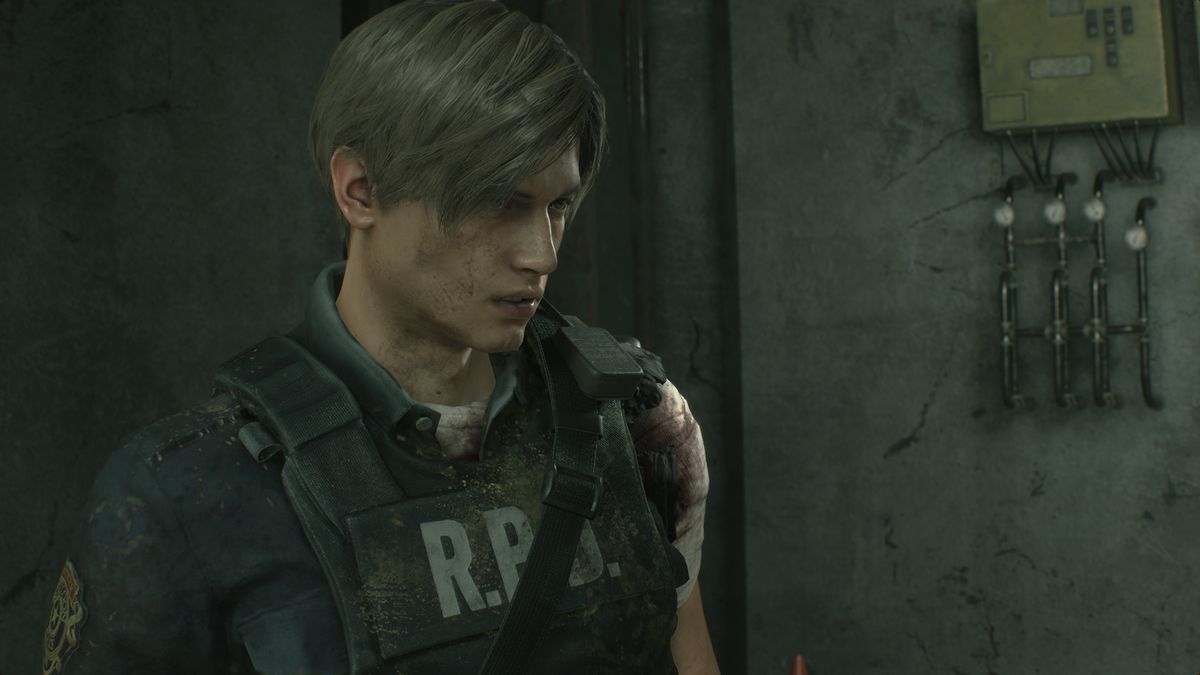 Leon Kennedy yang terluka dan berlapis tanah berdiri di fasilitas bawah tanah dalam tangkapan layar dari pembuatan ulang Resident Evil 2.