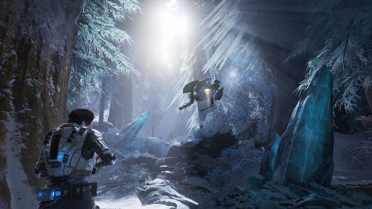 Kait berjalan melalui hutan es di Gears 5 dengan robot melayang di atasnya